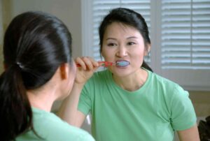 ASIAN WOMAN BRUSHING TEETH